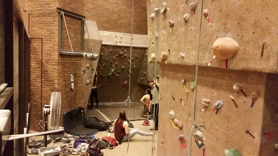 Several angled climbing walls surround climbers on the ground and on the walls