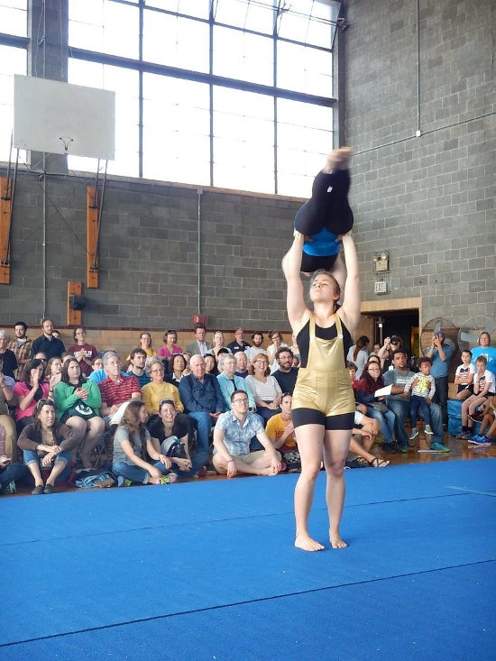 One performer holds another above her head, forming a T.