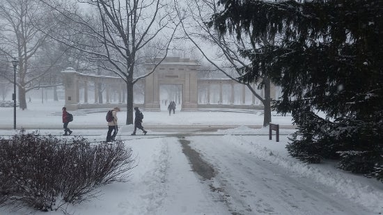 Students walk in the snow near the memorial arch
