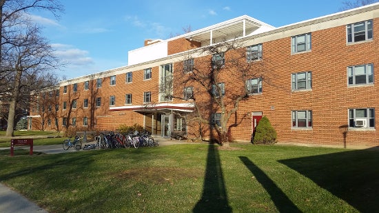 Three-story residence hall with a full bike rack by the front entrance