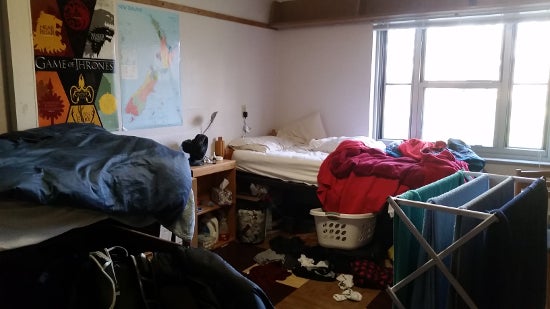 Messy room with unmade beds, towels drying on a rack