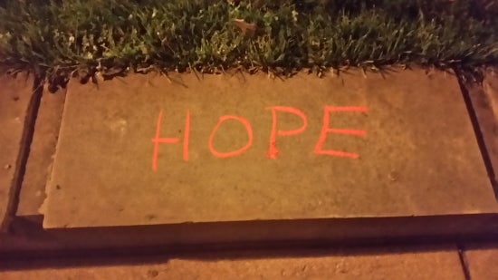 The word "hope" chalked on a stone in the sidewalk