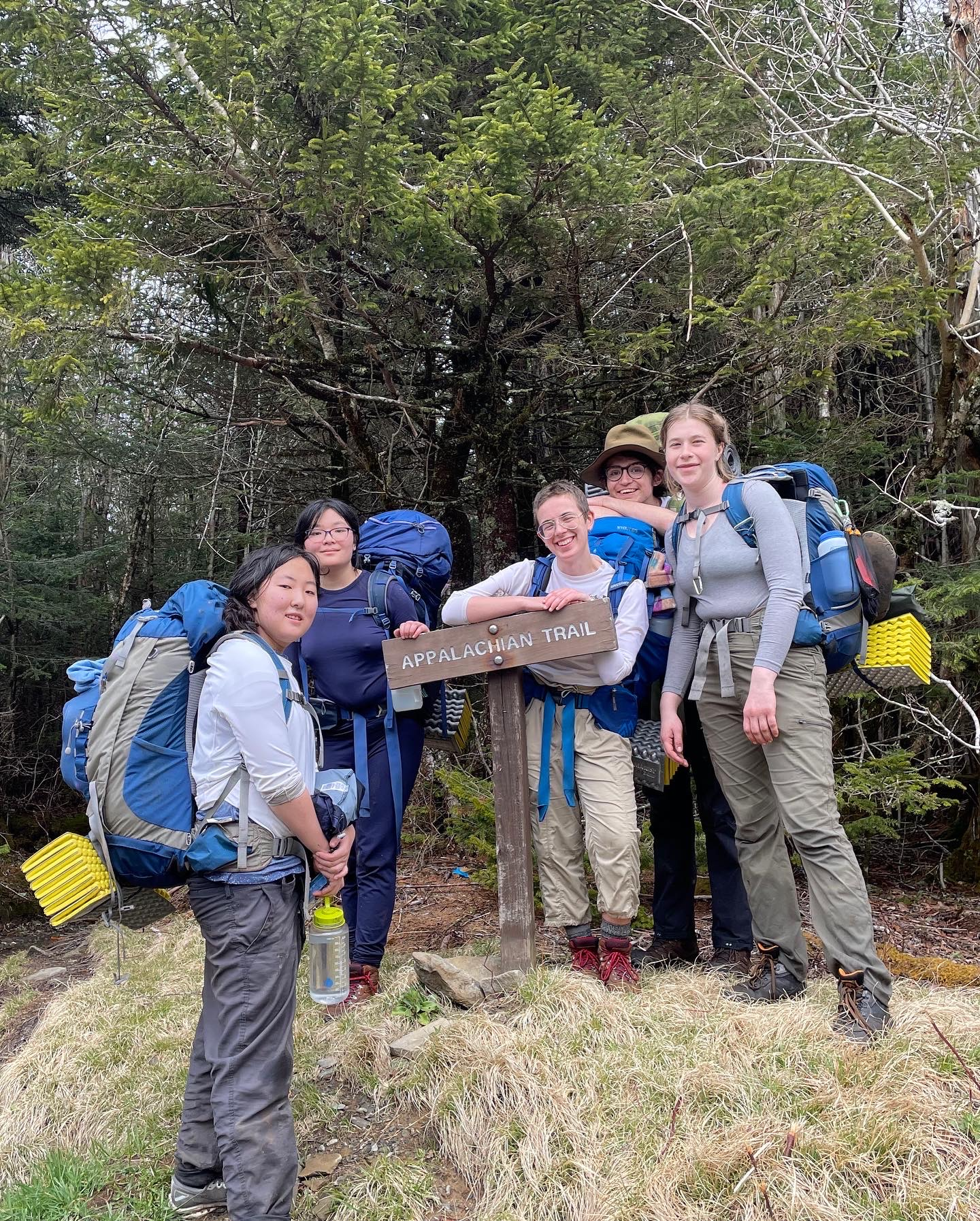 five smiling people stand around a sign that says "Appalachian Trail"