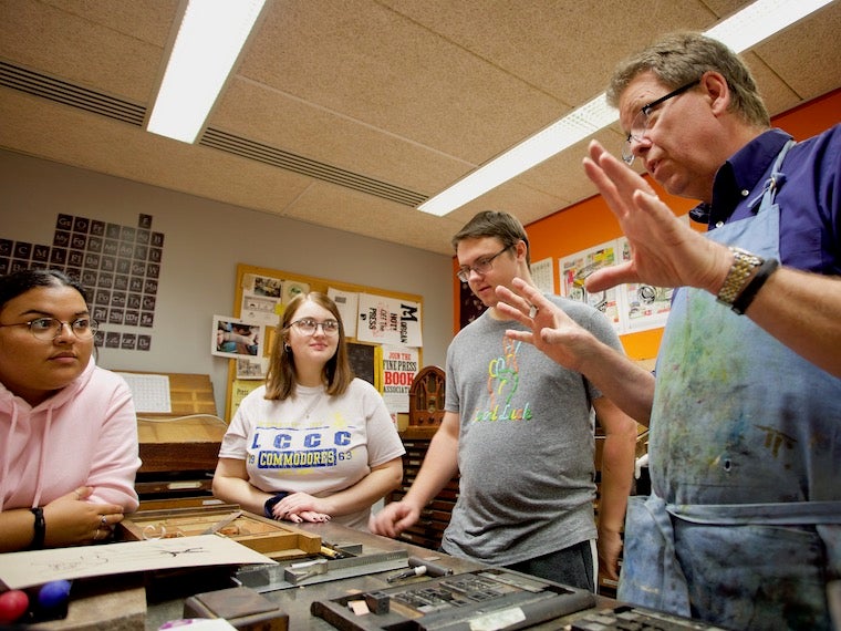 A letterpress teacher leads a workshop with students.
