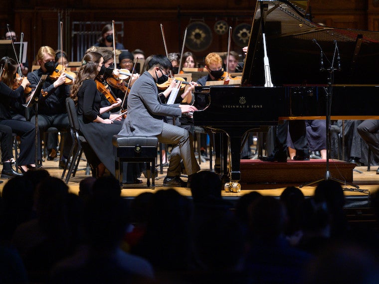 A piano player plays in front of an orchestra.