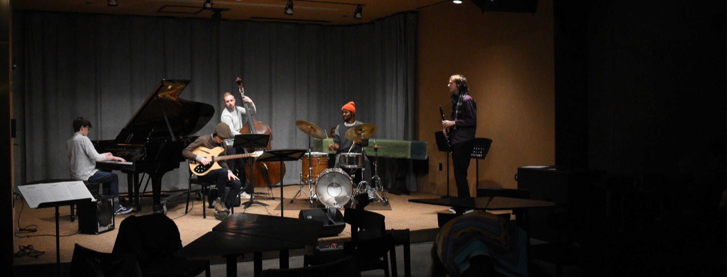 A jazz quintet performs on stage in a small venue.