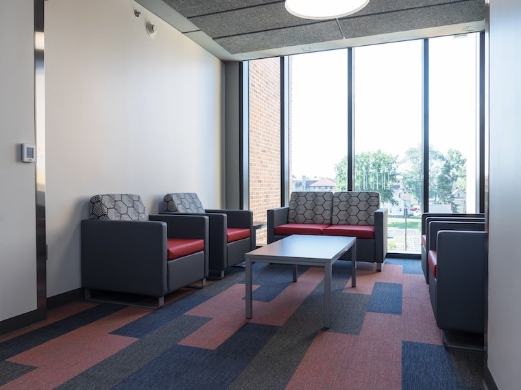 Small lounge area with armchairs, a sofa, and a coffee table near large windows.