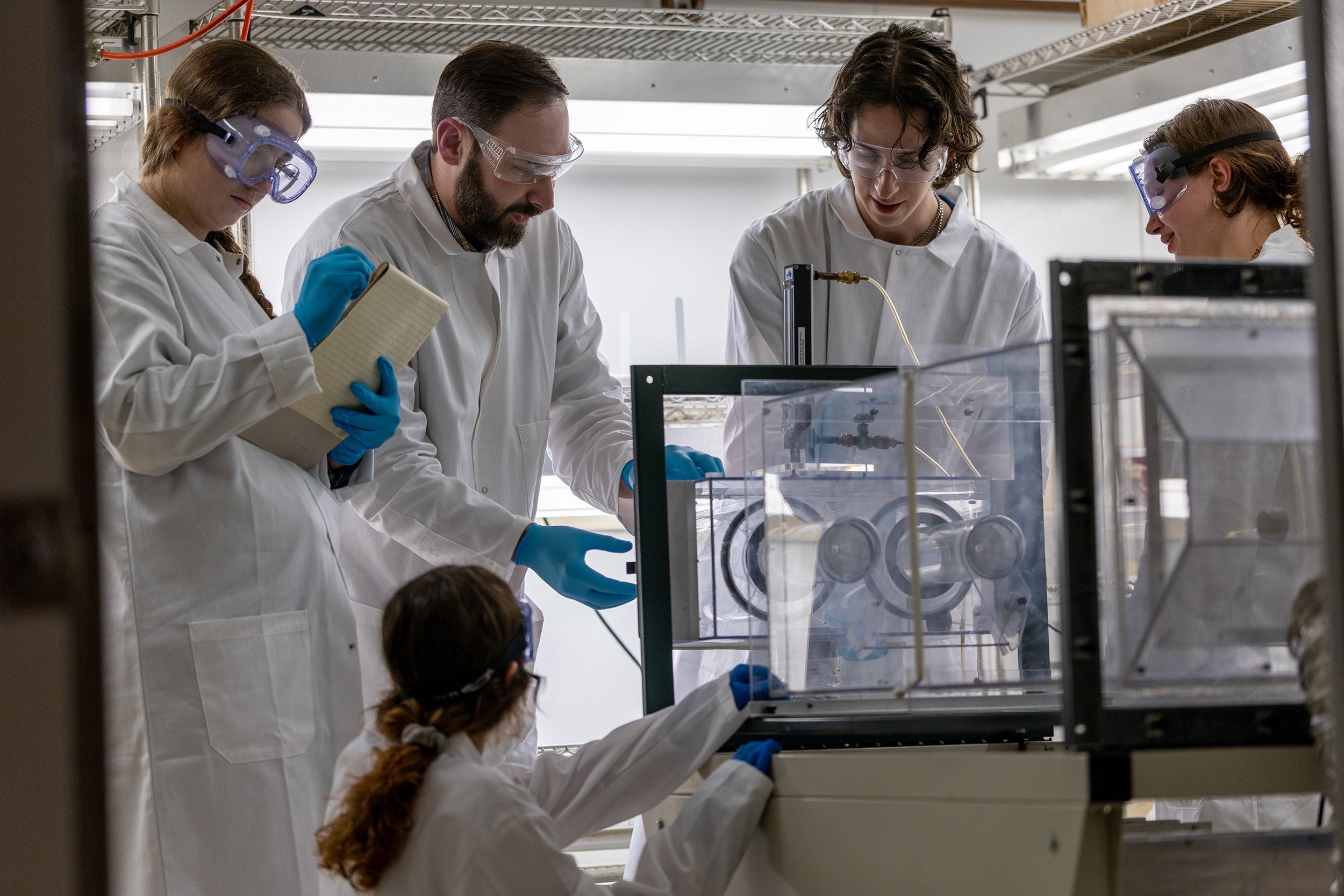 Five people in white lab coats working with medical equipment.