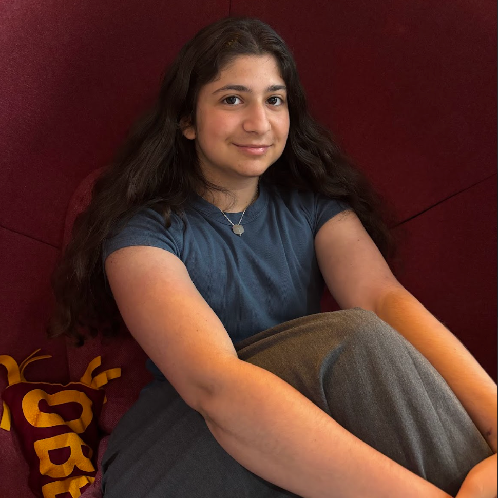 An Oberlin student with long dark hair sitting in a red chair.