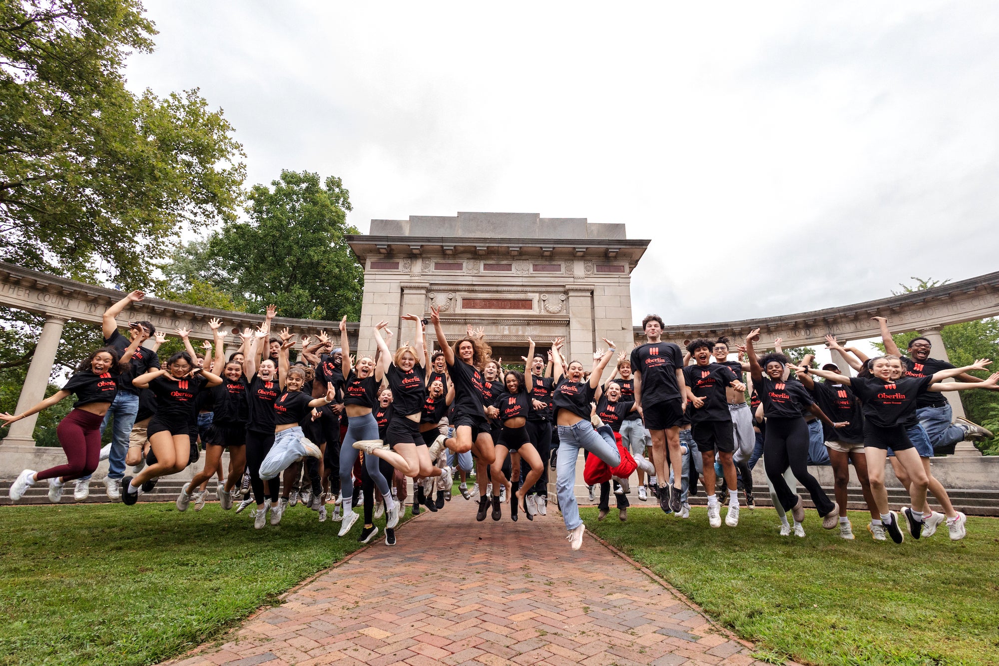 students cheerfully leaping in unison on Tappan Square.