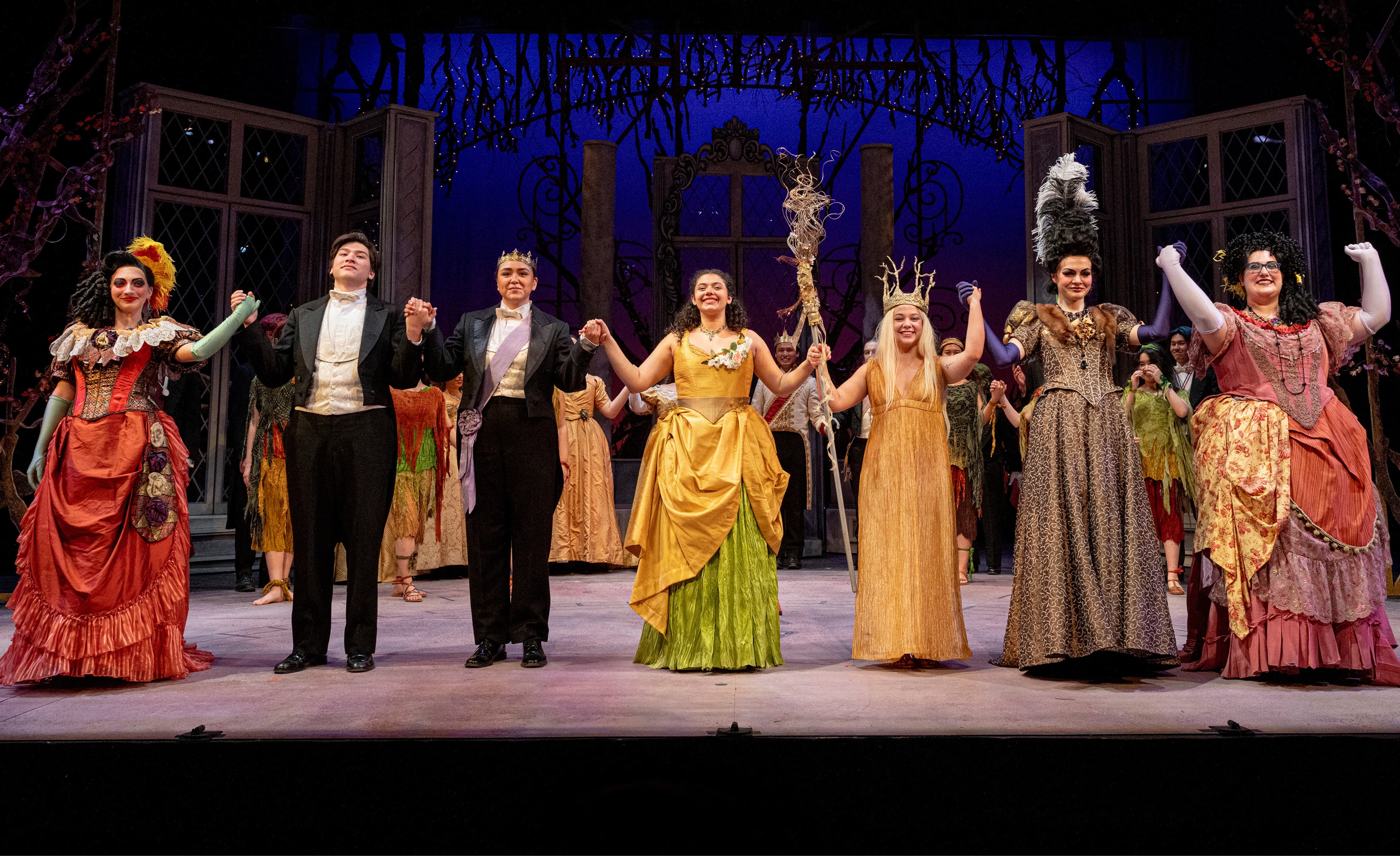 Actors in period costumes taking a bow on stage after a theatrical performance.