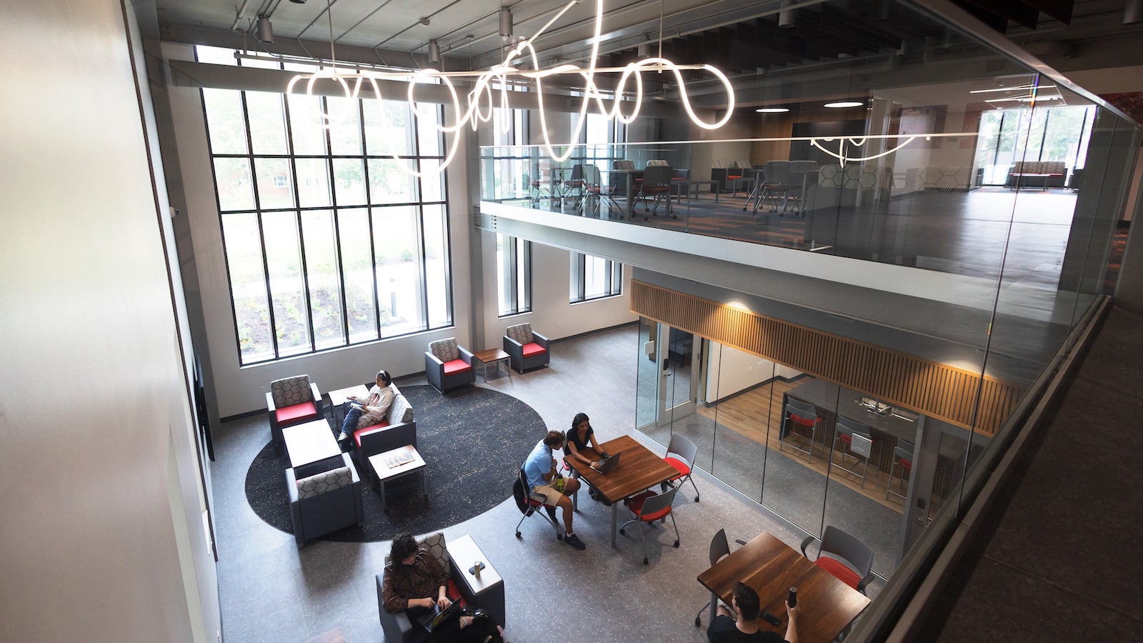 students studying at tables in a sunlit building.