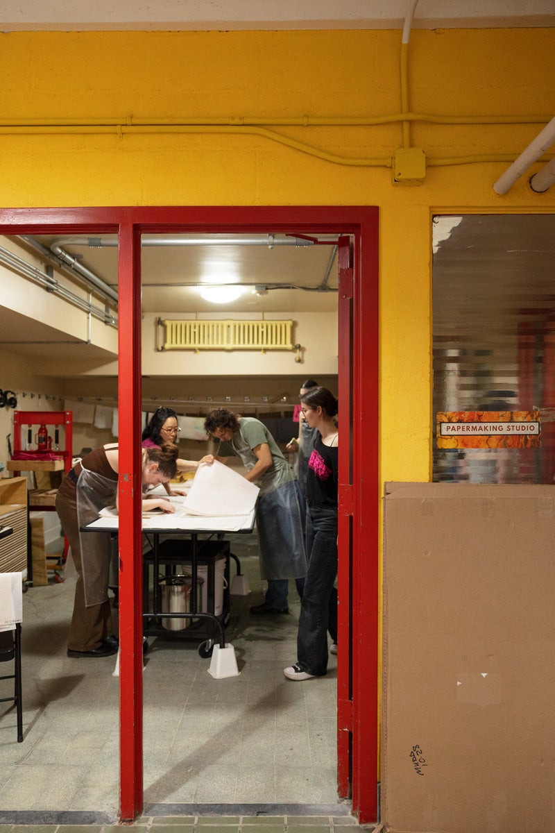 a far-away view of people making paper in a studio
