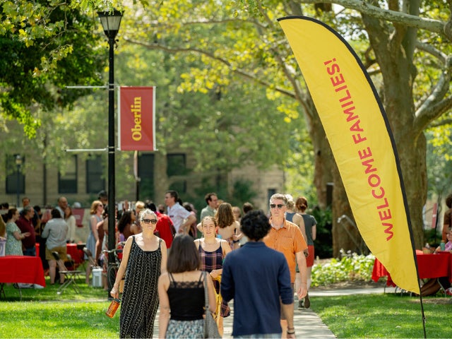 Students and family walking by yellow "welcome familes" flad and red "oberlin" sign