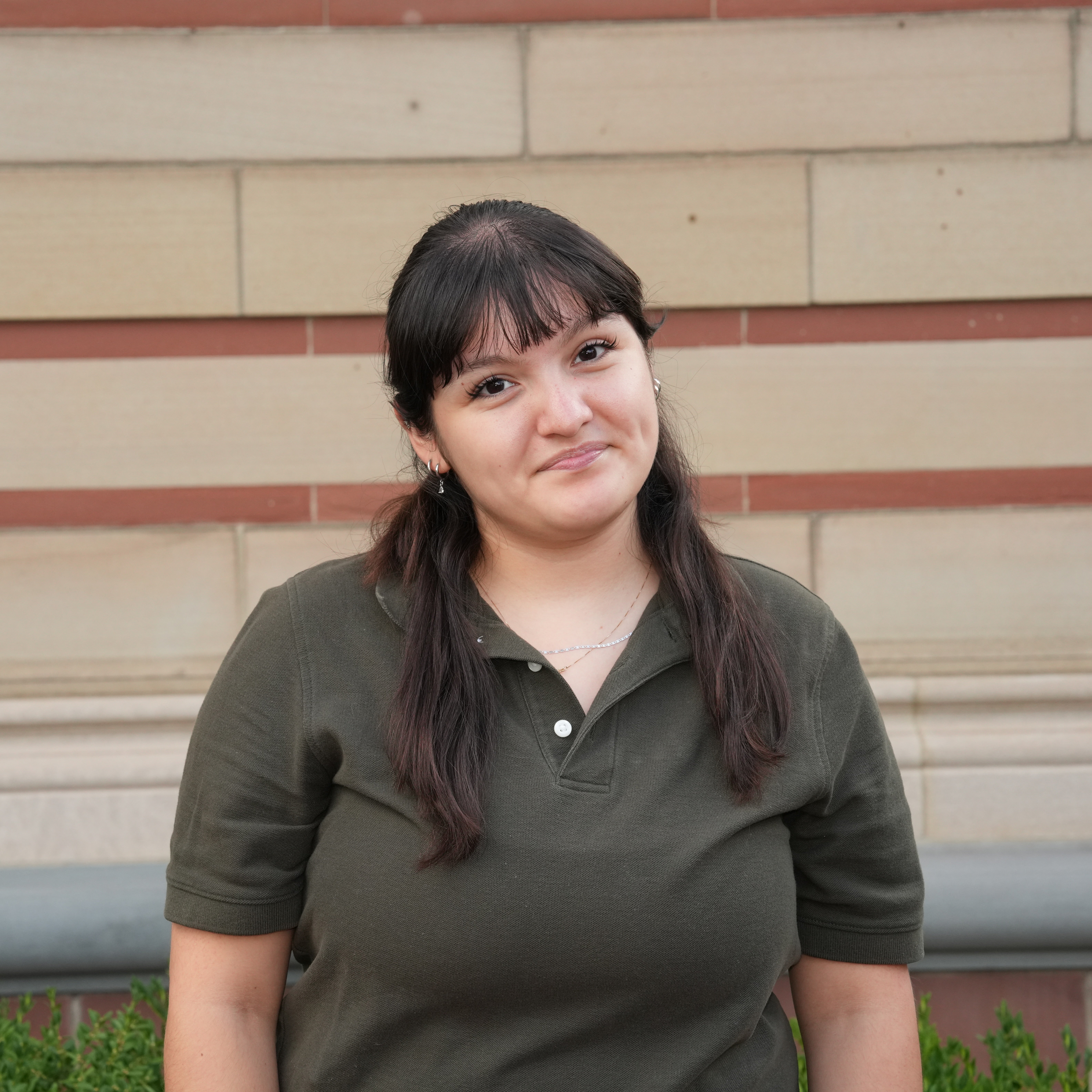A headshot of a female student in a dark green polo shirt.