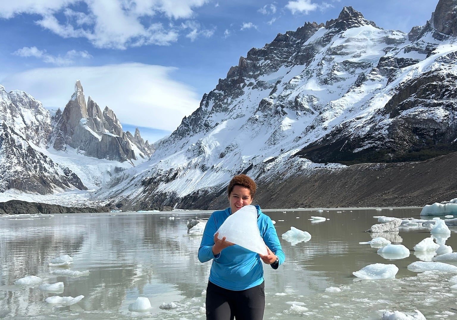 Grace Gordon holding a block of ice in front of mountains.