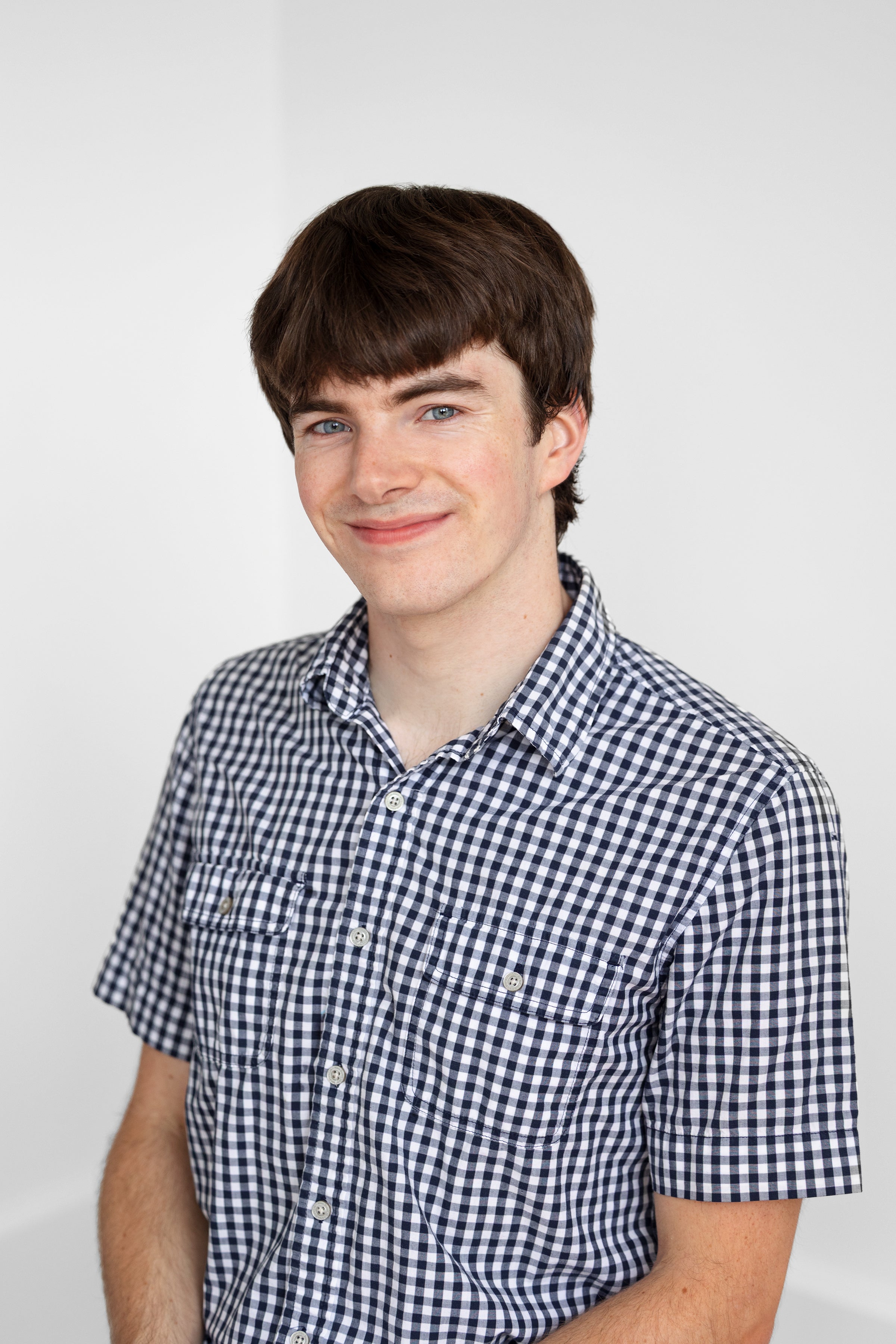 Noah Lyford smiles while wearing a blue and white checked shirt.