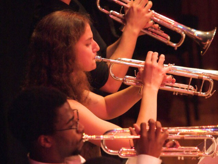 three students playing trumpet 