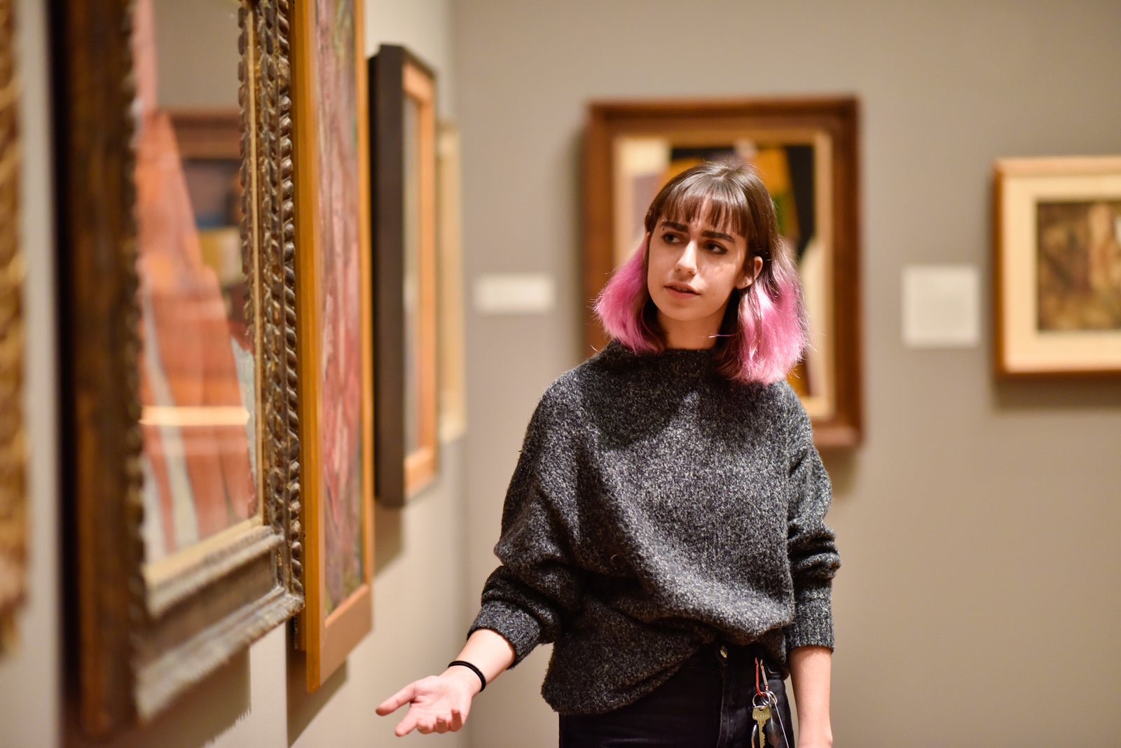 A student gives a talk in front of a painting in the museum.