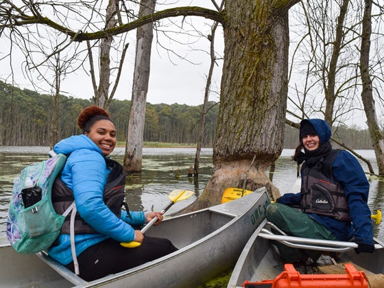Two students prepare to go out in canoes.