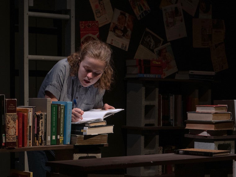 young girl sitting at a desk writing in a journal.
