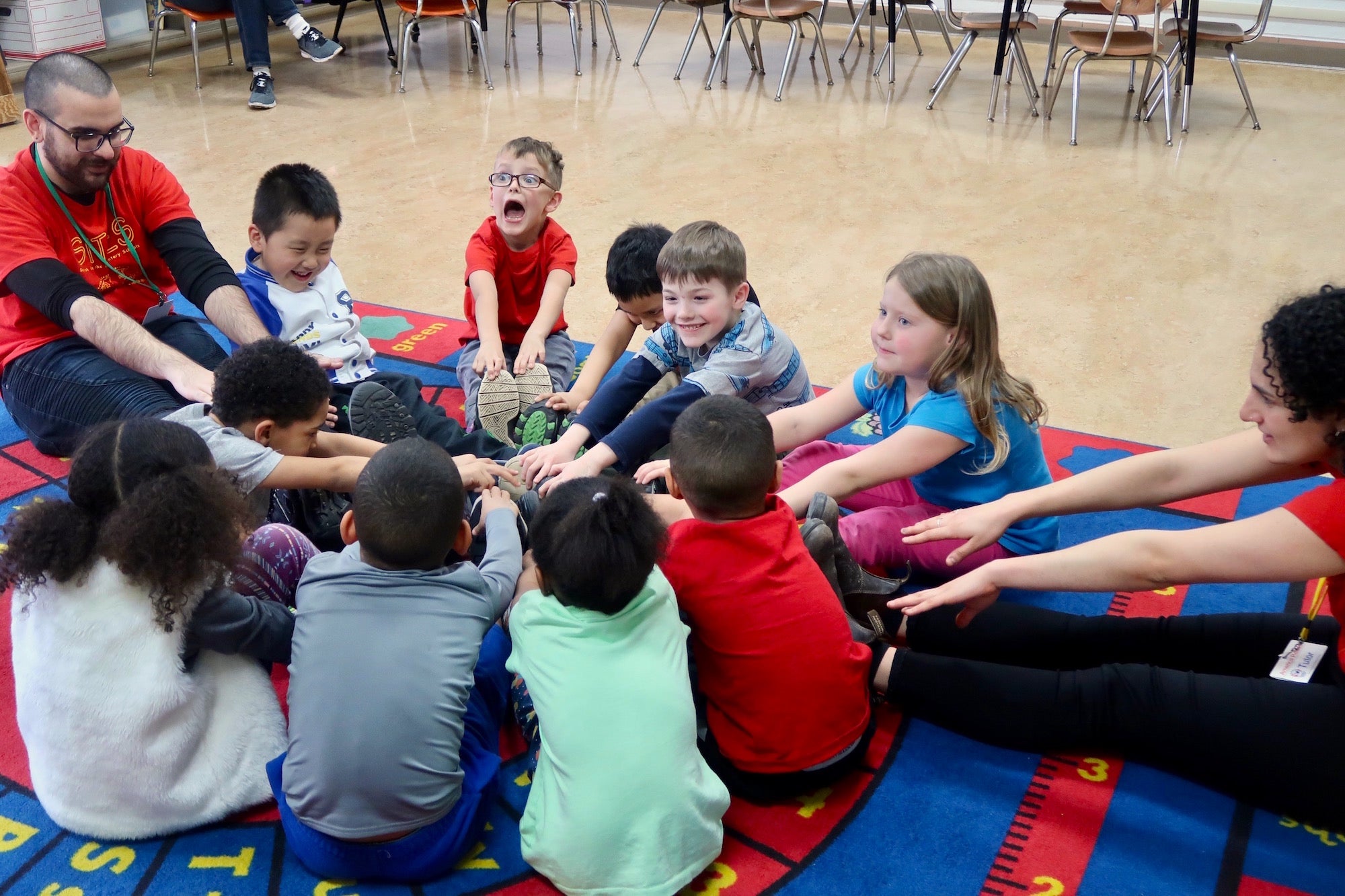 Sites Class with Kim Faber children sitting in circle with arms extended.