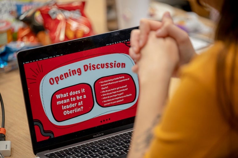 An open laptop shows a slide titled Opening Discussion: What does it mean to be a leader at Oberlin?
