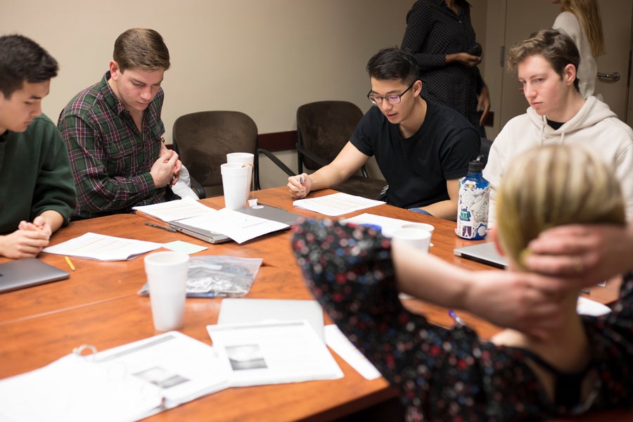 A group of students around a table review documents.