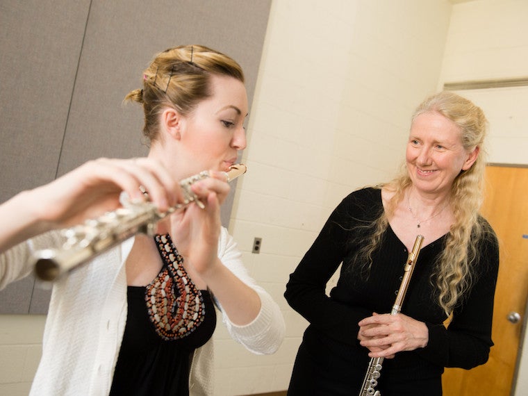 Instructor smiles at student playing flute