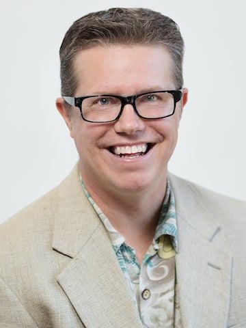 portrait of Brad Melzer who wears glasses and had a tan sport coat and printed shirt.
