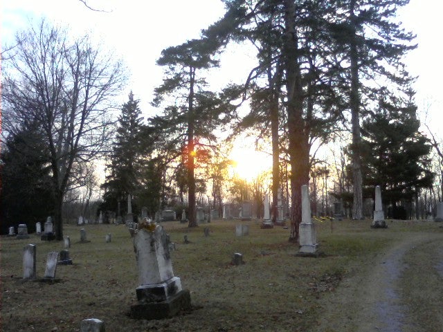 Old gravestones, with the sun over the horizon.