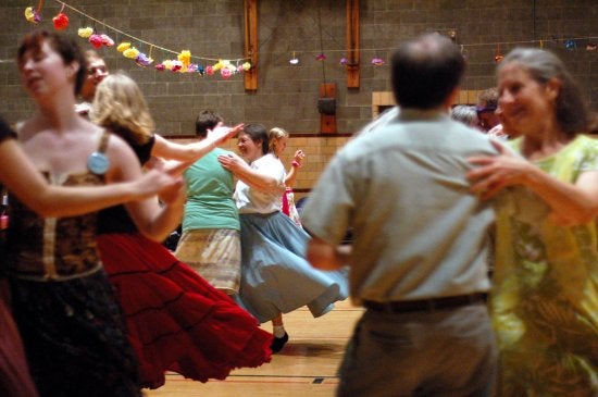 A group of people partner dance in a gym
