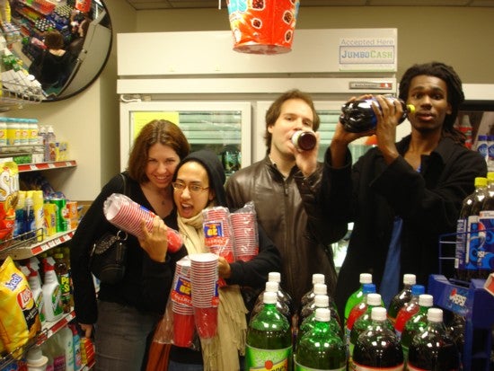 Holding up packages of cups and soda in a store.
