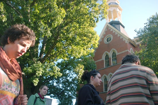 A group of students outside of the New Union Center. It is a tall building with a pointed roof and a tower