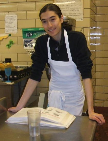 Student posing and leaning in front of a cookbook