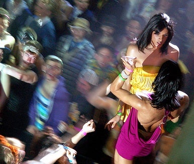 Drag performers performing on the Sco stage surrounded by cheering students in drag 