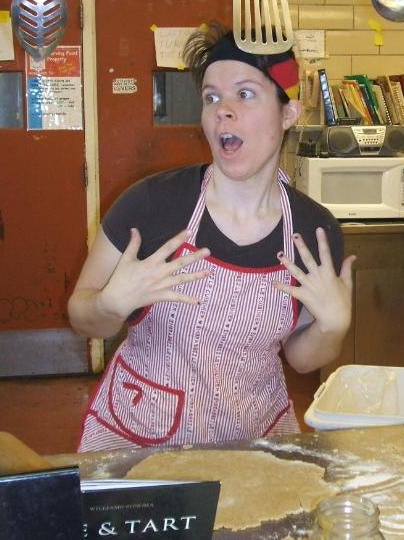 Student posing in astonishment wearing an apron in front of dough