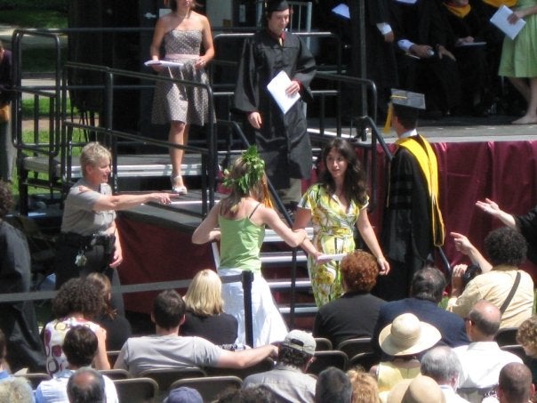 Liz approaches Aries, who is walking off the Commencement stage with diploma in hand.