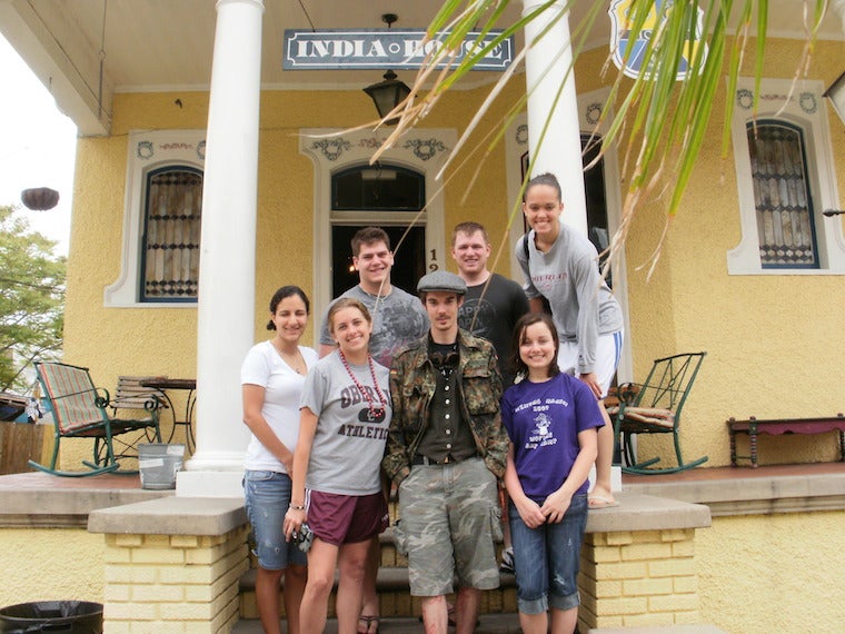 A group of students pose in front of a porch