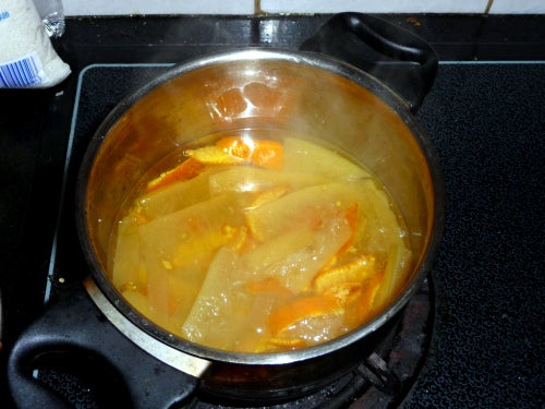 A pot on the stove containing fruit pieces and liquid.