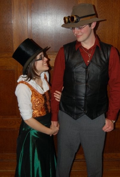 Two students holding hands wearing steam punk outfits 