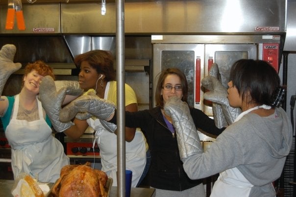 Students dance in a kitchen wearing oven mits