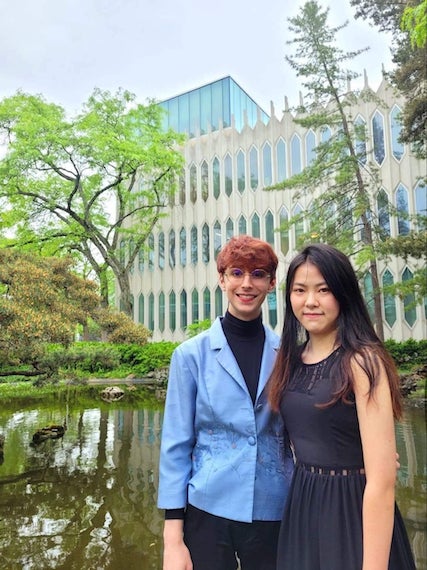 Ben and Jiaming standing and smiling in front of the Oberlin Conservatory koi pond.