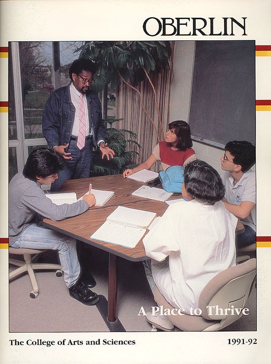 A professor in a suit speaks to students around a table. Their clothes are woefully out of date and they all have pencils and paper, no computers. Heading: A Place to Thrive.