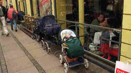 A baby sleeps in a stroller outside of a store 