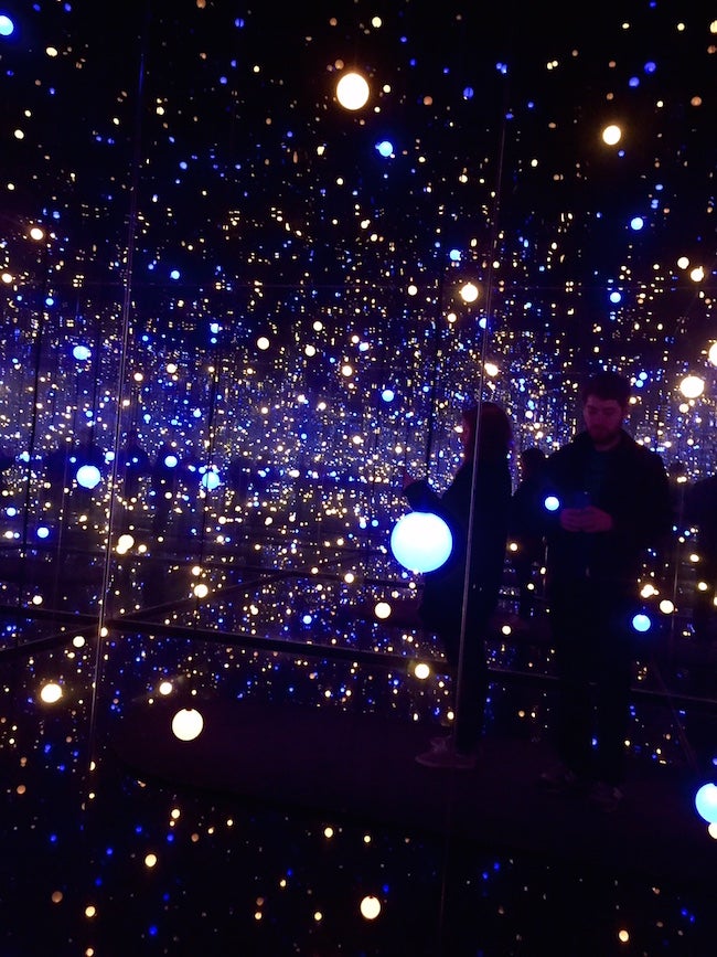 Two people in a mirrored room filled with lights