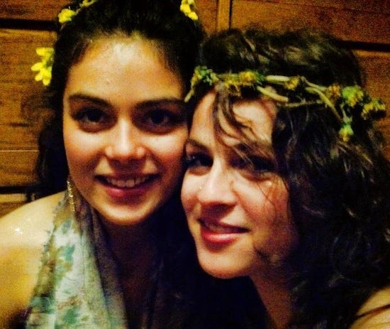 Georgia and her sister smiling and posing for a photo. Each are wearing flowers crowns and floral dresses