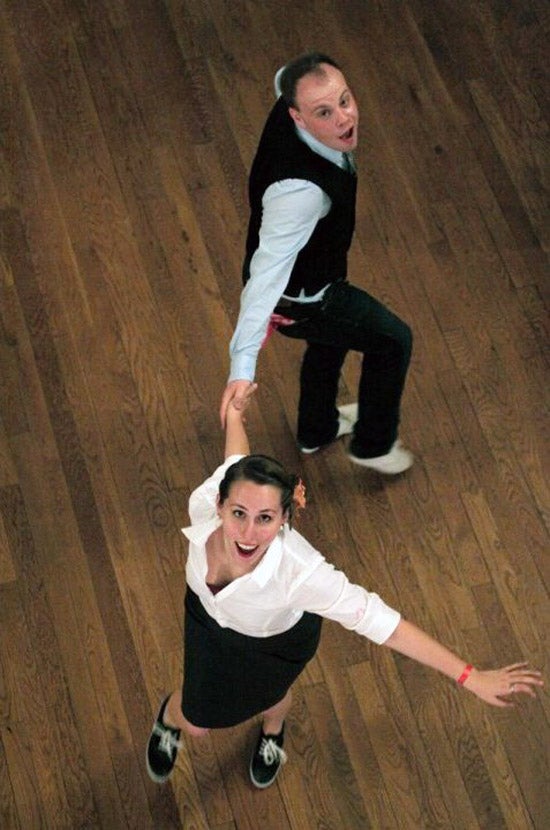 Two students partner dance and look at a camera up above