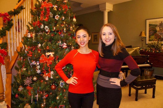 Two students pose in front of a christmas tree