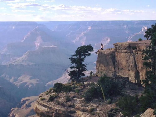 A hiker sits on a ridge of a canyon